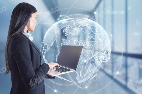 Preview: Attractive Young European Businesswoman Using Laptop In Blurry Office Interior With Globe Hologram