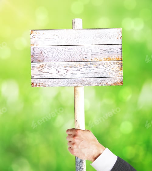 Preview: Businessman Hand Holding Empty Wooden Signboard On Green Background. Mock Up, 3D Rendering