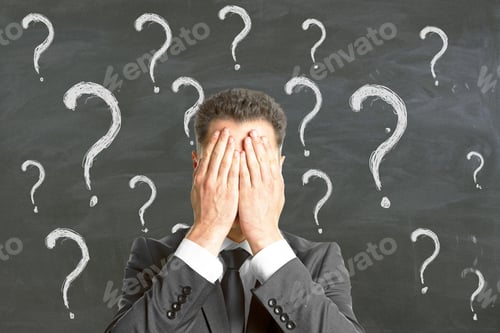 Preview: Young Businessman Covering Face With Palms On Chalkboard Background With Question Mark Sketches