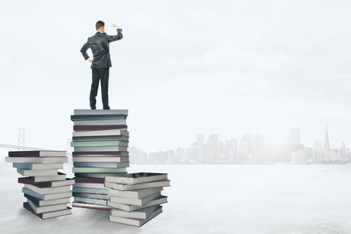 Preview: Back View Of Young Businessman Standing On Abstract Book Pile And Looking Into The Distance On