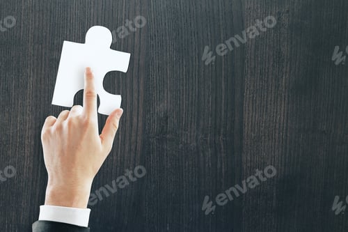 Preview: Hand Pointing At Jigsaw Piece On Wooden Background With Copy Space. Teamwork, Communication And
