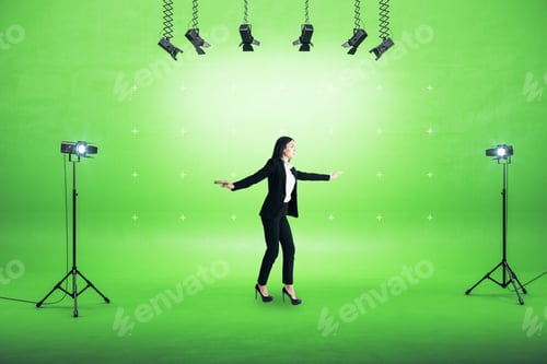 Preview: Businesswoman Standing In Photo Studio With Spotlight And Blank Gren Wall. Stage Concept And Copy