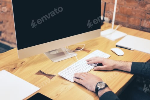 Preview: Side View Of Businessman Hands Using Computer On Wooden Desk Top And Blurry Red Brick Wall
