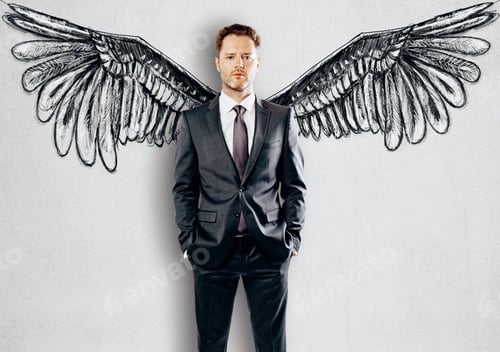 Preview: Handsome Young Businessman In Suit Standing Against Concrete Wall With Wings Sketching. Freedom