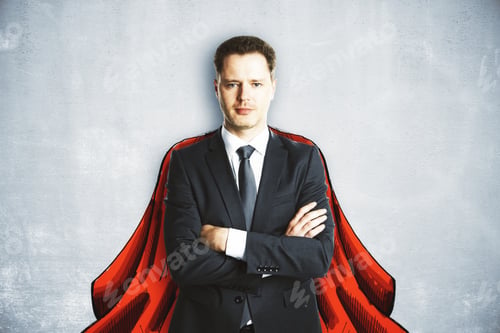 Preview: Handsome Young European Businessman With Drawn Cape On Concrete Wall Background. Hero Concept