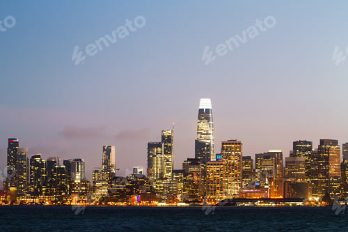 Preview: Modern Waterfront San Francisco City Skyline Background With Illuminated Buildings At Dawn. Urban