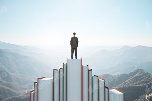Preview: Back View Of Businessman Standing On Book Mountain On Sky Background With Mock Up Place. Education