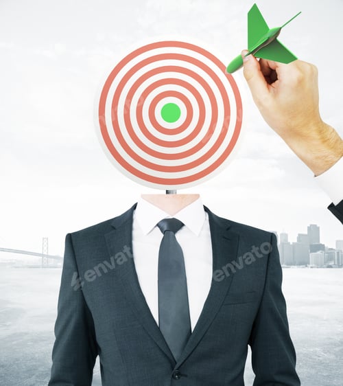 Preview: Hand With Green Dart Aiming At Target-Headed Businessman On City Background. Aiming And Targeting