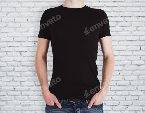 Preview: Man Wearing Empty Black Shirt On Brick Wall Background. Advertisement And Design Concept. Mock Up