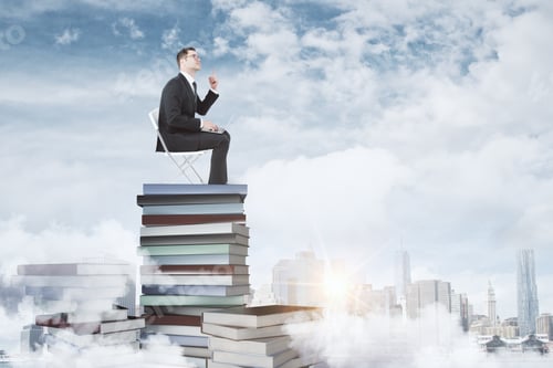 Preview: Education Concept With Businessman Sitting On Pile Of Books With Laptop That Found A Solution At