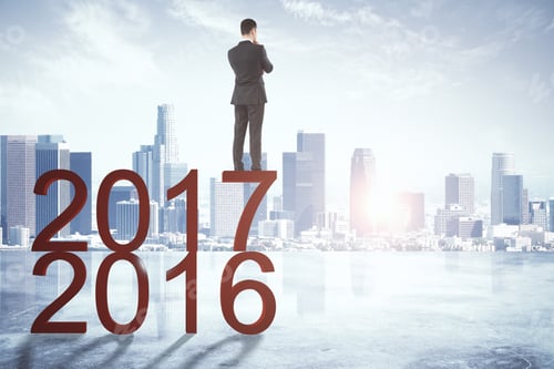 Preview: Back View Of Young Businessman Looking Forward To New Year 2018 On Abstract City Background With