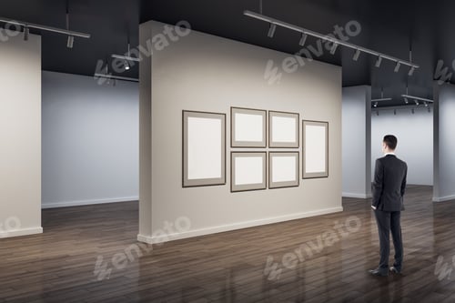 Preview: Businessman In Modern Concrete Exhibition Hall Interior Looking At Blank White Mock Up Posters On