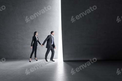 Preview: Side View Of Businessman And Woman Holding Hands And Stepping Into The Light From Behind A Concrete