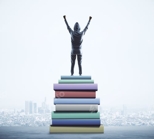 Preview: Back View Of Young Hacker Standing On Pile Of Books On Blurry City Background. Education And