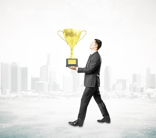 Preview: Businessman Carrying Golden Cup Trophy On Foggy City Background