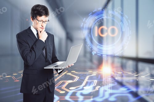 Preview: Attractive Young European Businessman Using Laptop In Blurry Office Interior With Ico Hologram