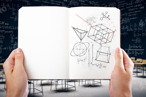 Preview: Hand Holding Copybook With Creative Geometric Figures Sketch On Blurry Classroom Interior