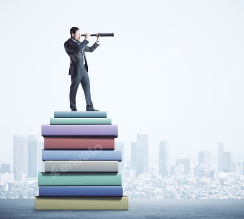 Preview: Attractive Young European Businessman Using Telescope While Standing On Pile Of Books On Blurry