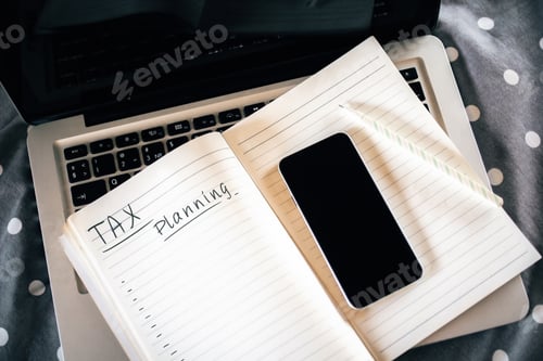 Preview: Top View Of Notepad And Empty Smartphone Placed On Laptop Keyboard. Tax Planning Concept. Close Up