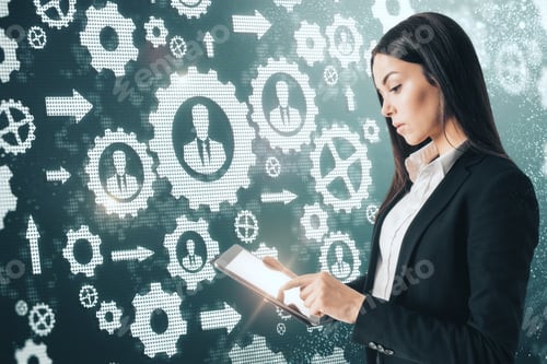 Preview: Side View Of Attractive Young European Businesswoman Using Tablet On Abstract Cogwheels Background.