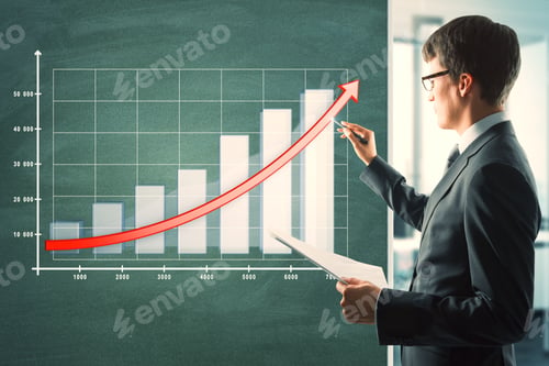 Preview: Attractive Young European Businessman With Business Chart On Chalkboard. Finance And Seminar Concept