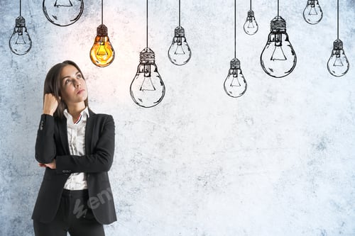 Preview: Businesswoman Thinking And Drawing Yellow Lamps On Grey Concrete Wall. Innovation And Leadership