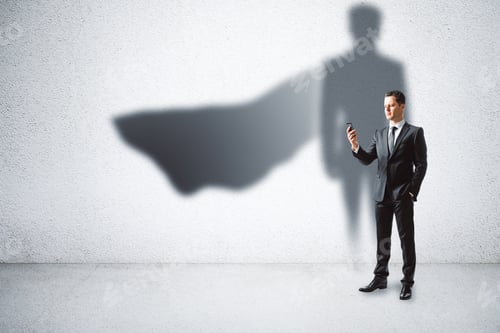 Preview: European Businessman With Super Hero Cape Shadow Standing On Concrete Wall Background. Leadership