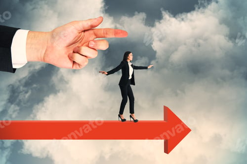 Preview: Side View Of Hand Pointing At Attractive Young European Businesswoman Balancing On Red Arrow