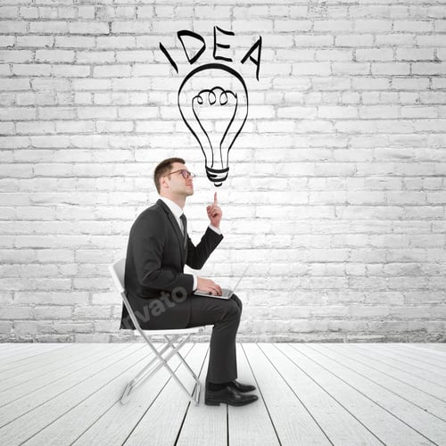 Preview: Businessman Sitting In Brick Room With Notebook And Pointing To Lamp