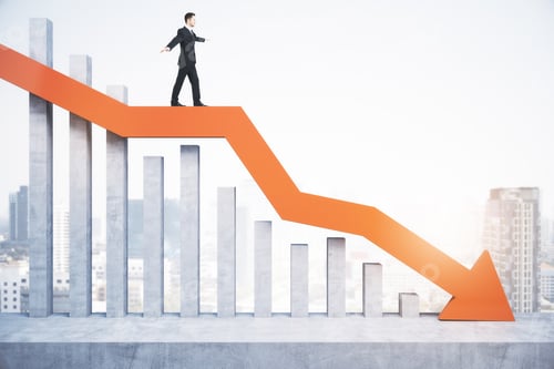 Preview: Attractive Tiny European Male Standing And Balancing On Abstract Red Downward Chart Arrow On Light