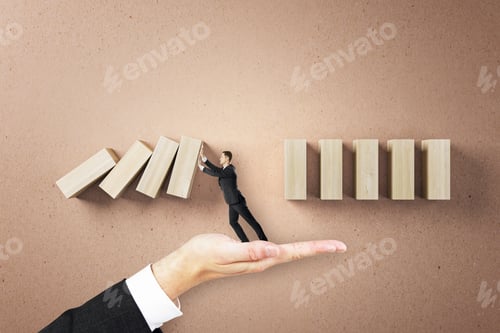 Preview: Businessman Hand Holding Abstract Falling Wooden Blocks On Brown Wall Background. Financial, Crisis