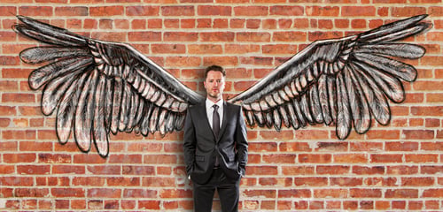 Preview: Young Businessman In Suit With Creative Drawn Wings On Red Brick Wall Background