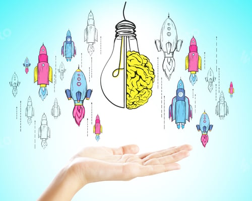 Preview: Hand Holding Creative Startup Sketch With Drawn Rockets And Light Bulb On Subtle Blue Background