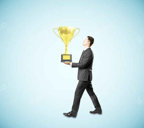 Preview: Businessman Carrying Golden Cup Trophy On Blue Background