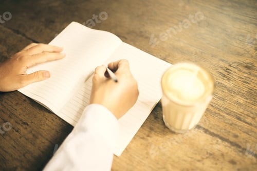 Preview: Woman Writes In A Notebook On A Wooden Desk With A Cup Of Coffee