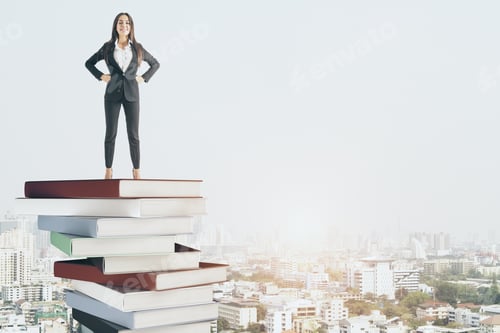 Preview: Attractive Young Businesswoman Standing On Pile Of Books On City Background. Success And Education