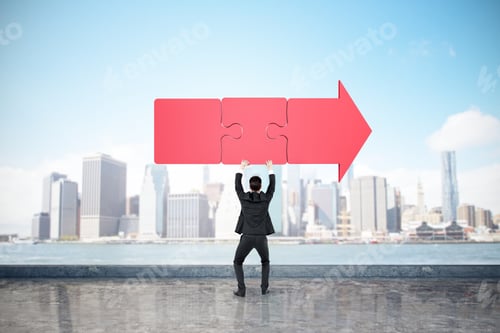 Preview: Back View Of Young Businessman Holding Red Puzzle Arrow On Bright Blue Sky And Blurry City