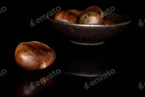 Preview: Lot Of Whole Edible Brown Chestnut Front Focus In Glazed Bowl Isolated On Black Glass