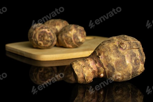 Preview: Group Of Four Whole Fresh Brown Jerusalem Artichoke On Bamboo Cutting Board Isolated On Black Glass