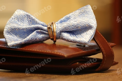 Preview: Bowtie and Gold Rings on a Brown Wallet