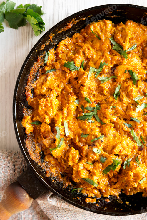 Preview: Homemade Chicken Tikka Masala In A Cast Iron Pan On A White Wooden Background, Top View. Flat Lay