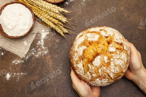 Preview: Male Hands Are Holding Freshly Baked Bread. Wheat Ears, Wooden Rolling Pins And A Bowls Of Flour