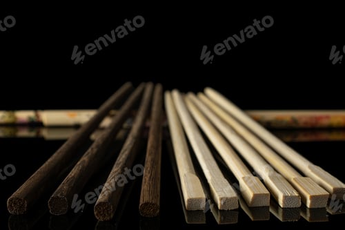 Preview: Lot Of Whole Asian Brown Chopsticks In Row Isolated On Black Glass