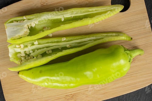 Preview: Group Of One Whole Two Halves Of Hot Green Pepper Banana On Bamboo Cutting Board Flatlay On Grey