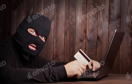 Preview: Hacker Holding A Credit Card On Wooden Background