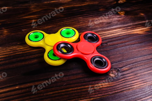 Preview: Yellow And Red Fidget Spinners On Rustic Wooden Desk