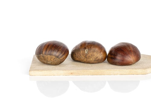 Preview: Group Of Three Whole Edible Brown Chestnut On Wooden Cutting Board Isolated On White Background