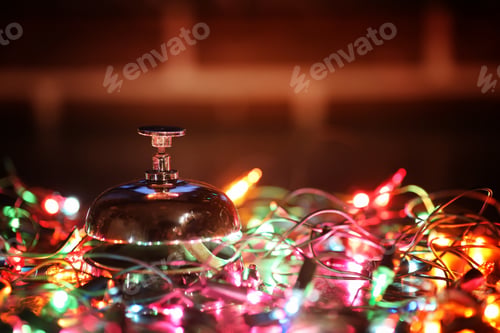 Preview: Reception Bell On The Table And Color Shining Garland On Background