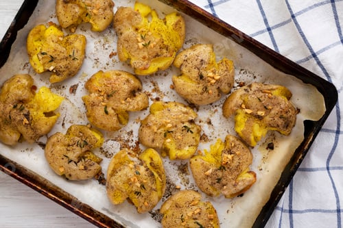 Preview: View From Above, Homemade Garlic Thyme Smashed Potatoes On A Baking Sheet, Top View. Flat Lay
