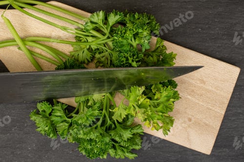 Preview: Lot Of Whole Fresh Green Parsley On Wooden Cutting Board With Steel Knife Flatlay On Grey Stone
